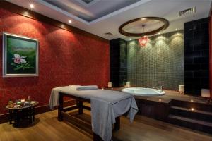 a bathroom with red walls and a tub and a table at Orange County Belek in Belek