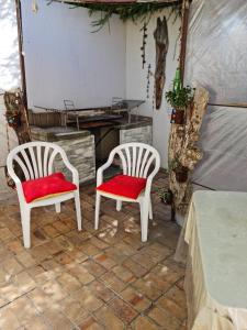 Duas cadeiras brancas com almofadas vermelhas num pátio em Angel's Corner em Cidade do Cabo