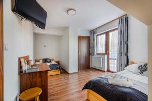 a bedroom with two beds and a desk and a television at Apartamenty Majerczyk in Zakopane