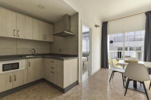 a kitchen with white cabinets and a table with chairs at Apartamento Bregador in Playa de San Juan