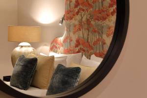 a mirror reflecting a couch with pillows and a vase at The Harcourt Arms in Stanton Harcourt