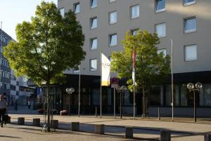 ein Gebäude mit Flaggen und Bäumen davor in der Unterkunft PLAZA Hotel Hanau in Hanau am Main