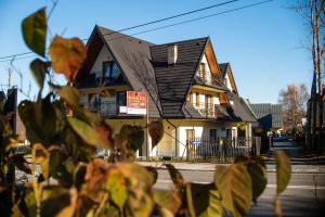 a house with a black roof on a street at Apartamenty Majerczyk in Zakopane