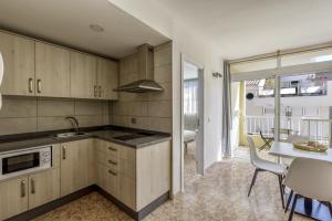 kuchnia z drewnianymi szafkami i stołem oraz jadalnia w obiekcie Apartamento Albatros w mieście Playa de San Juan
