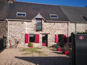 une maison en briques avec des volets rouges sur les fenêtres dans l'établissement Nid douillet en Foret de Broceliande, à Ploërmel