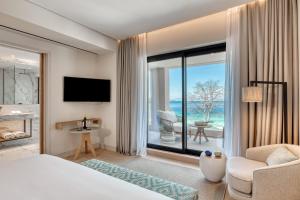a hotel room with a bed and a large window at Vathi Cove Luxury Resort & Spa in Chrysi Ammoudia