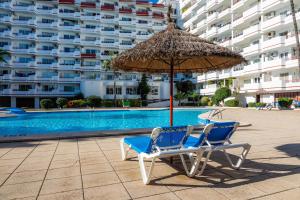 due sedie e un ombrellone accanto alla piscina di Apartamento Villa Cancun a Port d'Alcudia