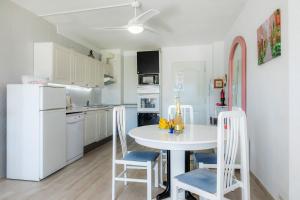 uma cozinha branca com uma mesa e cadeiras brancas em Apartamento Villa Cancun em Port d'Alcudia
