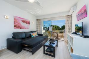 ein Wohnzimmer mit einem schwarzen Sofa und einem TV in der Unterkunft Apartamento Villa Cancun in Port d'Alcúdia