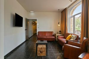 a living room with leather furniture and a tv at Villa Renard in De Panne