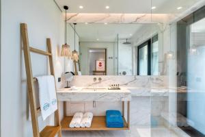 a bathroom with a sink and a large mirror at Vathi Cove Luxury Resort & Spa in Chrysi Ammoudia
