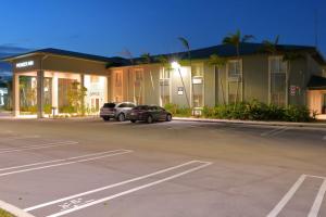 un estacionamiento con autos estacionados frente a un edificio en Pioneer Inn, en West Palm Beach