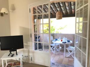 Zimmer mit einem Tisch, einem TV und einem Fenster in der Unterkunft 06D - Appartement spacieux avec terrasses, jardin et piscine in Roquefort-les-Pins