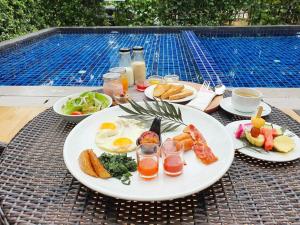 een bord met ontbijtproducten op een tafel naast een zwembad bij Fortune Courtyard Khao Yai Hotel Official in Mu Si