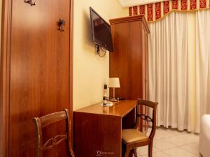 ローマにあるアラ バシリカ ルームスのデスク、テレビ、ベッドが備わる客室です。