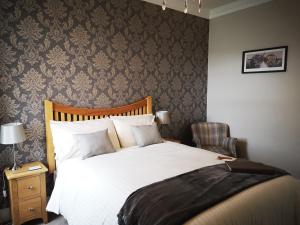 a bedroom with a large white bed and a chair at Lossiemouth House in Lossiemouth