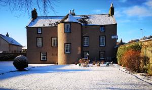 un gran edificio de ladrillo con nieve en el suelo en Lossiemouth House en Lossiemouth