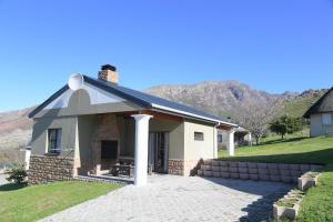 a small white house with a porch and mountains in the background at ATKV Goudini Spa in Rawsonville