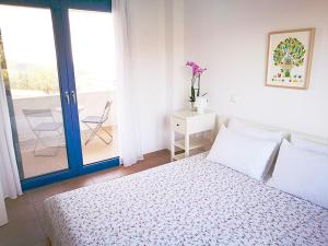 a white bedroom with a bed and a balcony at Olive Bay Hilltop Apartments Ammouliani in Ammouliani