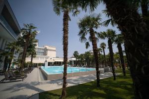 a swimming pool with palm trees in front of a building at Hotel Terme Venezia in Abano Terme