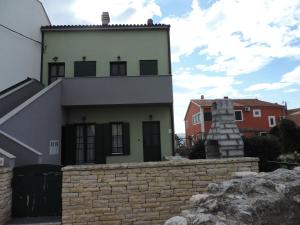 a house with a stone wall in front of a building at Apartments Lori in Biograd na Moru