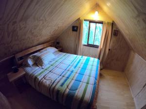 um pequeno quarto com uma cama no sótão em Cabañas Llaima em Melipeuco