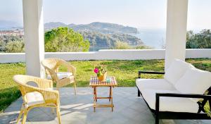 a porch with chairs and a table with flowers on it at Olive Bay Hilltop Apartments Ammouliani in Ammouliani