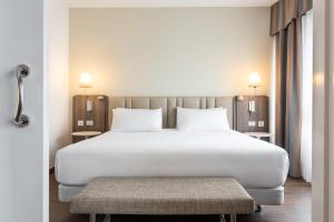 a bedroom with a large white bed and a bench at Eurostars Atlántico in A Coruña