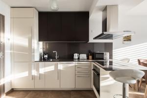 a kitchen with white cabinets and black appliances at Lucy by Quokka 360 - a stone's throw from the station in Massagno