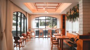 a restaurant with wooden tables and chairs and windows at Li CALLA Resort Trat in Trat