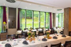 un ristorante con tavoli e sedie bianchi e ampie finestre di Hotel Waldmühle a Zella-Mehlis
