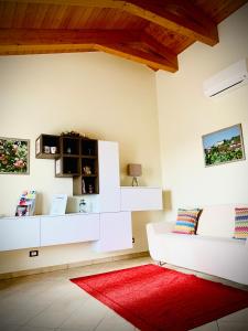 a living room with white furniture and a red rug at Agriturismo Cascina Mariale in Albiano dʼIvrea