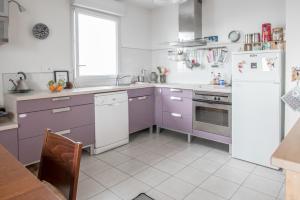 - une cuisine avec des placards violets et un réfrigérateur blanc dans l'établissement LE VOYAGEUR - Appartement avec vue mer, à Saint-Nazaire