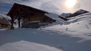 a cabin in the snow with the sun behind it at Hôtel et Appart'Hôtel Restaurant L'Adray in Longefoy