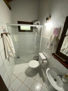 a white bathroom with a toilet and a sink at Pousada Villa São Pedro in Garopaba