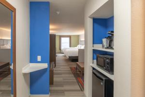 un couloir d'une chambre d'hôtel avec un lit et une cuisine dans l'établissement Holiday Inn Express & Suites N Waco Area - West, an IHG Hotel, à West