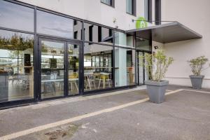 a building with large glass windows and tables at Campanile Rennes Sud - Saint Jacques in Saint-Jacques-de-la-Lande