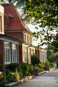 una casa de ladrillo rojo con ventanas blancas en una calle en Hotel Bethanien en Langeoog