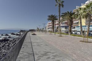 a sidewalk next to a beach with palm trees and buildings at Apartamento Pardela in Playa de San Juan