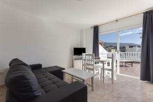 a living room with a black couch and a table and chairs at Apartamento Pardela in Playa de San Juan