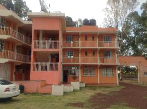 an orange building with a car parked in front of it at Hotel La Loma in Huasca de Ocampo