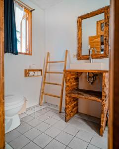 een badkamer met een wastafel, een spiegel en een toilet bij Rascal House Gili Trawangan in Gili Trawangan