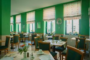 a restaurant with green walls and tables and chairs at Hotel Adagio in Leipzig