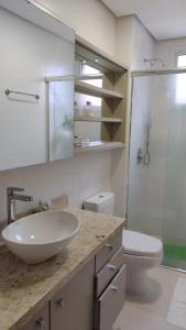 a bathroom with a sink and a shower and a toilet at Apto a uma quadra do mar em torres in Torres