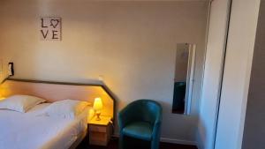 a bedroom with a bed and a chair and a lamp at Résidence Wilson in Le Mont-Dore