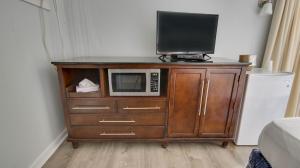 a television on top of a wooden cabinet with a microwave at Rideau Oceanfront Motel in Ocean City
