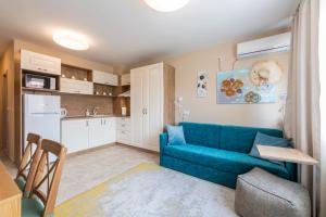 een woonkamer met een blauwe bank en een keuken bij Aquamarine in Pomorie