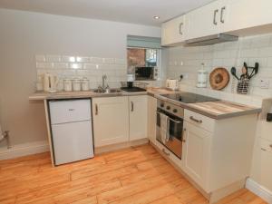 a kitchen with white appliances and a wooden floor at The Snug in Matlock