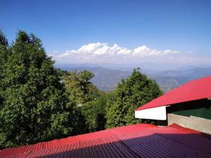 a red roof of a building with trees in the background at Janjua lodges Murree in Murree