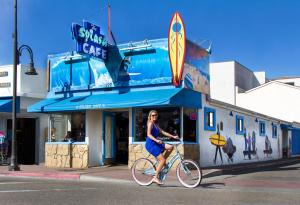 Una donna in bicicletta davanti a un bar per surfisti di SeaVenture Beach Hotel a Pismo Beach